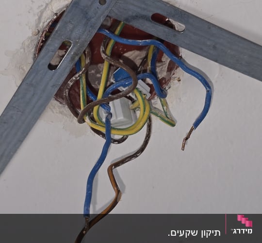 חוטי חשמל חשופים בקיר עם תושבת מתכת